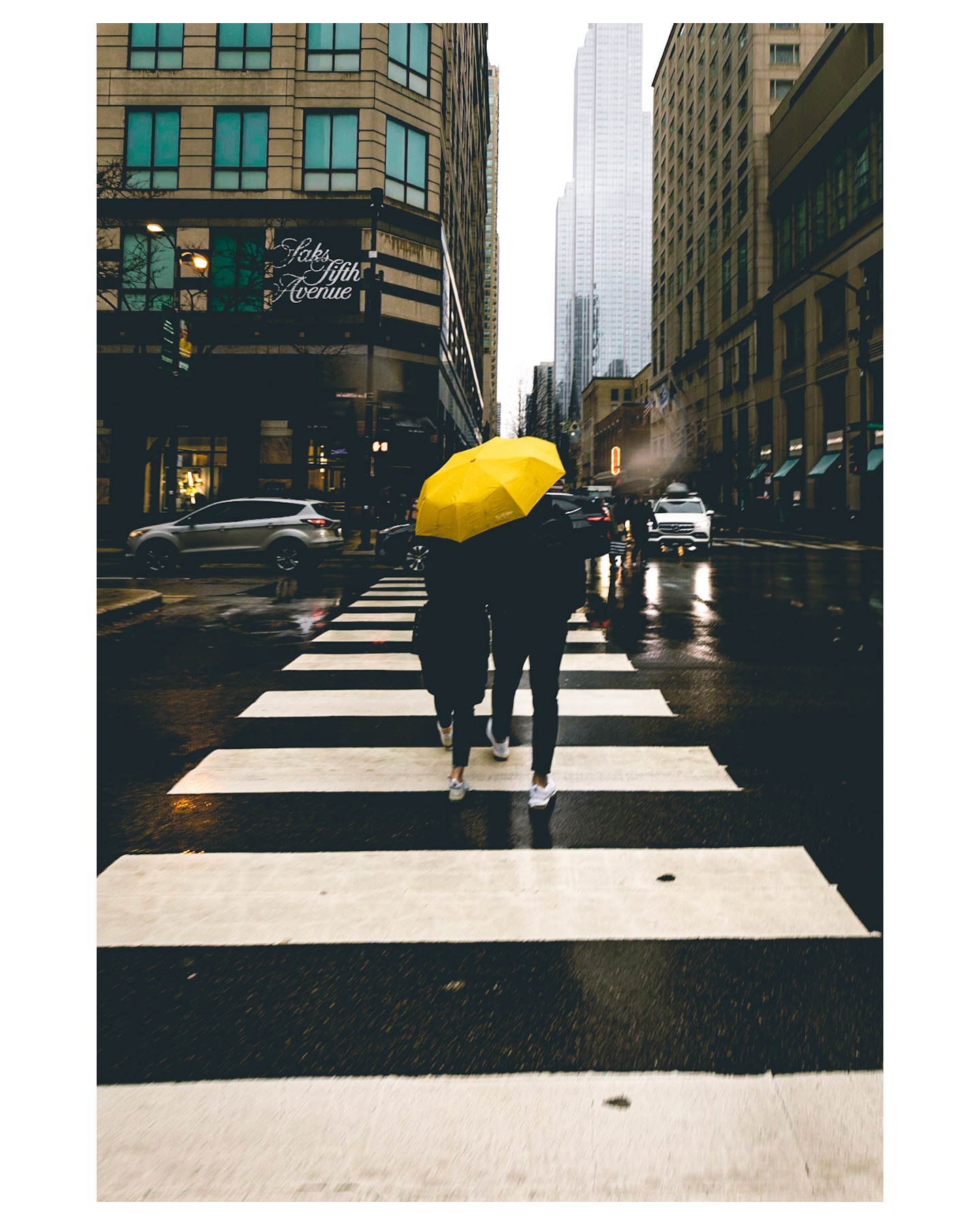 A yellow umbrella crosses Michigan Avenue in the rain, with raindrops blurring the lens.